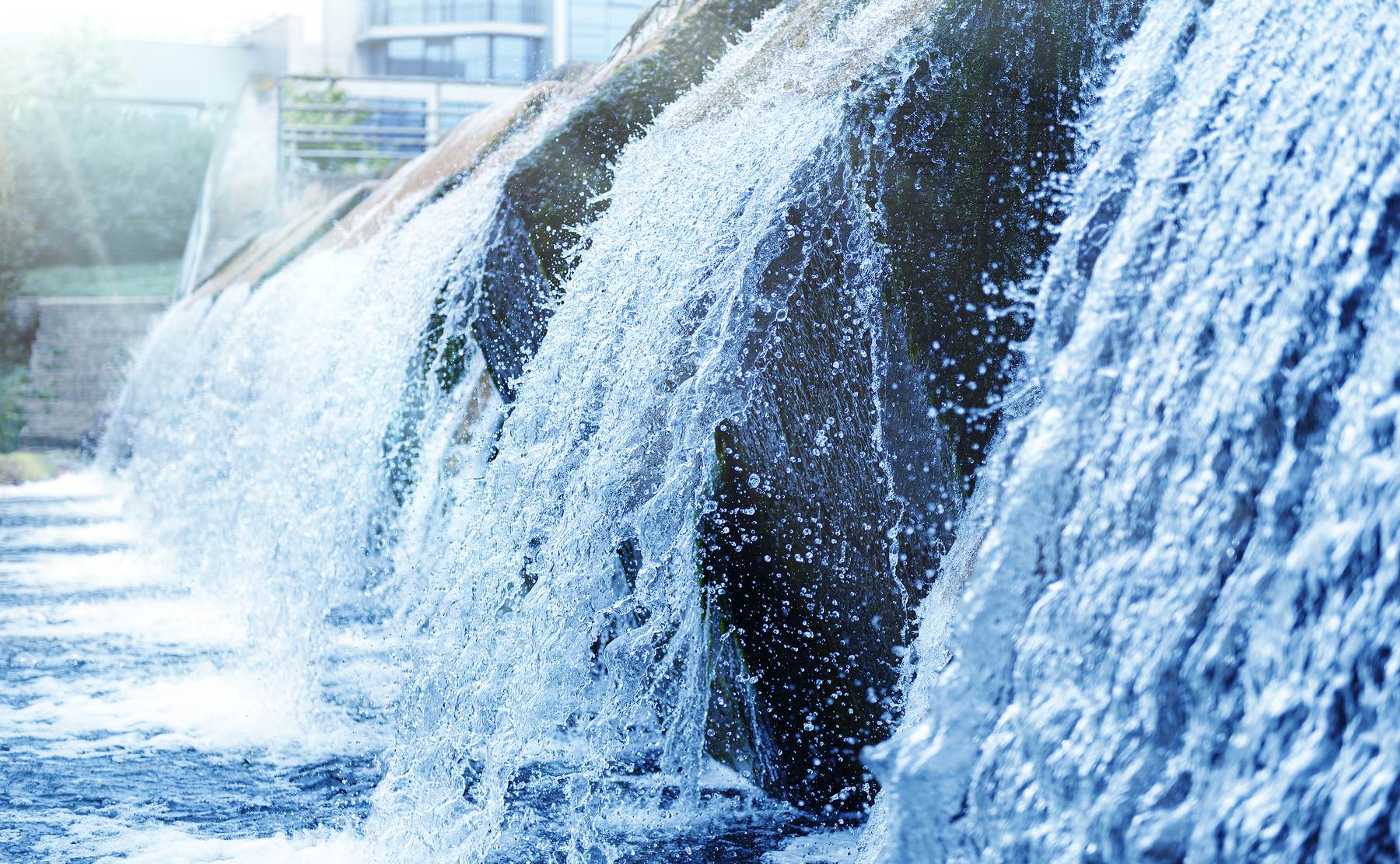 Water cascading over rocks near an urban waterway